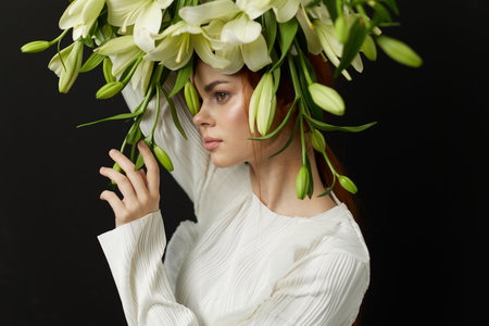 Young woman with long auburn hair wearing a white sweater, adorned with a large bouquet of white...