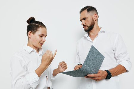 Businessman and professional discuss a document against a solid colored background, showcasing...