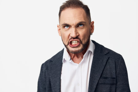 Business professional with intense expression stands against a solid colored background, portraying strong emotion, confidence, and determination in a studio corporate portrait.の写真素材