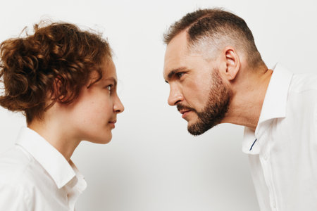 A professional man and colleague face off in a focused stance, capturing a strong business mood on an isolated colored background, conveying tension and clear intent.の写真素材