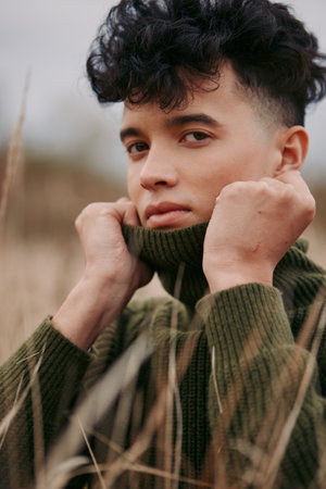 Close up portrait of a young man wearing a chunky knit sweater, showcasing authentic emotion and believable lighting that capture real character.の写真素材