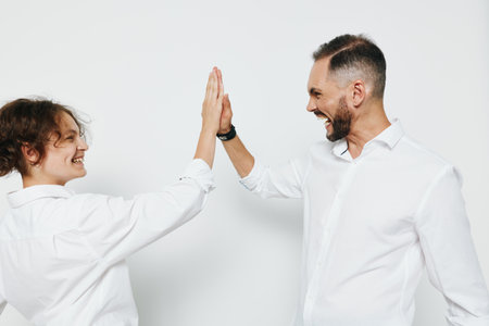 A confident business professional man and a colleague celebrate success with a high five on an isolated colored background, showcasing teamwork, emotion, and professional energy.の写真素材