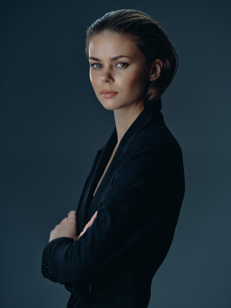 serious woman in black blazer with crossed arms posing indoors calm confident expressionの写真素材