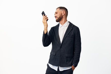 A professional man in a patterned blazer and white shirt checks his smartphone against an isolated colored background, displaying confident, reflective emotion.の写真素材