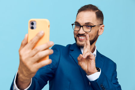 A professional man in a blue suit poses for a self portrait against a solid blue background, exuding confident, approachable energy and business style.の写真素材