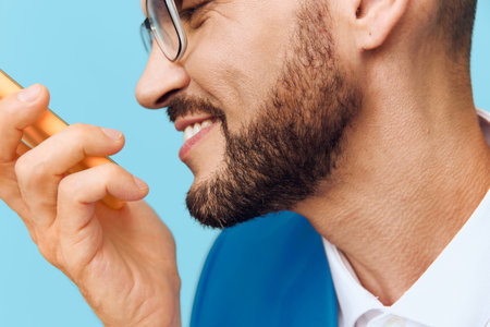 A professional businessman smiles with confidence and emotion against a solid blue background, conveying leadership, communication, and modern work presence.の写真素材