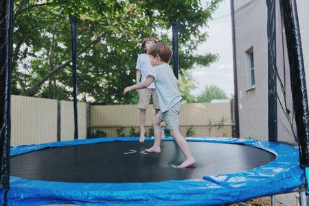 Happy children jumping on a trampoline, enjoying a sunny day outdoors. Their laughter fills the air as they embrace the joy of play and friendship.の写真素材