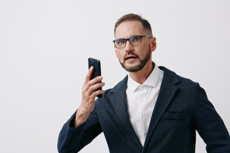 A focused business professional man speaks on a mobile phone, wearing a suit, with confident posture and intense gaze against an isolated colorful background.の写真素材