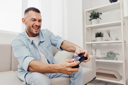 Engaged man playing video games at home, showcasing the balance between leisure and technology, reflecting modern challenges and self-care.の写真素材