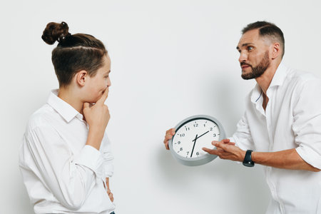 A professional business scene featuring a man in a white shirt engaged in a thoughtful moment. The other man gestures with a clock, conveying urgency and focus against an isolated color background.の写真素材