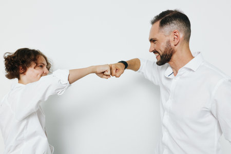 A professional businessman shares a confident fist bump with a colleague against an isolated colored background, signaling teamwork, ambition, and strong emotional energy in a corporate setting.の写真素材