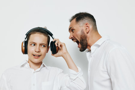 A professional businessman displays strong emotions while engaging with a younger figure against an...