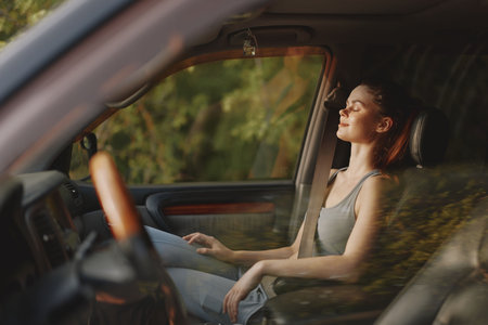 Young woman enjoying a moment of peace in a car, with sunlight illuminating her face, reflecting a sense of calm and tranquility during a road tripの写真素材
