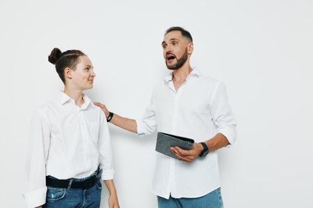 A confident male business professional speaks with enthusiasm to a colleague against a plain isolated colored background, gesturing with a tablet while showing energy, focus, and engagement.の写真素材