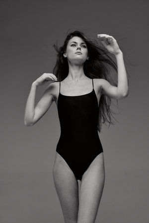 Black and white portrait of a woman in a black swimsuit posing with flowing hair and confident expressionの写真素材
