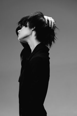 Black and white profile of a woman with short hair touching her head in a minimalist style.の写真素材