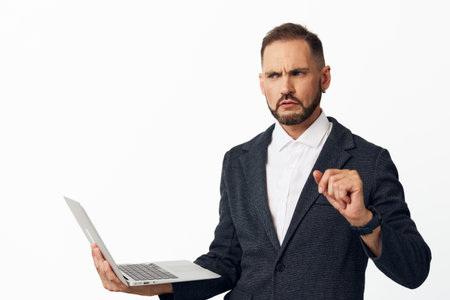 A corporate professional man on an isolated colored backdrop, holding a laptop and showing intense focus, determination, and confidence, capturing a moment of proactive business engagement.の写真素材