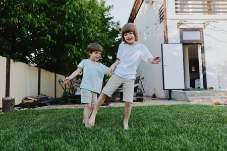 Playful children enjoying a sunny day, running on green grass with carefree expressions and bright outfits, capturing the joy of childhood.の写真素材