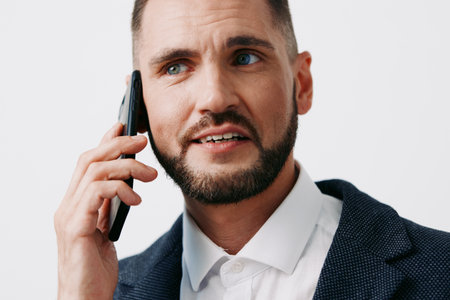 A focused business professional speaks on a mobile phone against an isolated colored background, signaling confidence, clarity, and proactive communication in a corporate setting.の写真素材
