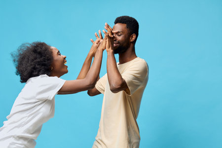 Happy couple playfully interacting against a vibrant blue background, showcasing joy and connection in casual attire, perfect for social media and lifestyle themesの写真素材