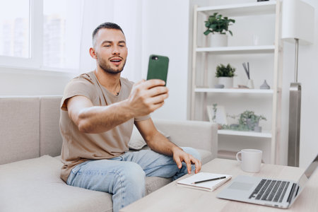 Smiling man engaged in a phone call, embracing emotional connection while practicing digital detox at home, surrounded by a minimalist workspace and soft colors.の写真素材