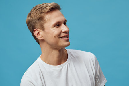 smiling young caucasian man white t-shirt look side isolated on blue background digital nomad remote...