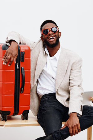Joyful smiling man with dark skin, wearing beige blazer, white shirt, and stylish sunglasses,...