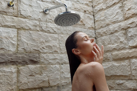 woman taking shower with water droplets on skin, natural stone background, relaxation, calm and...