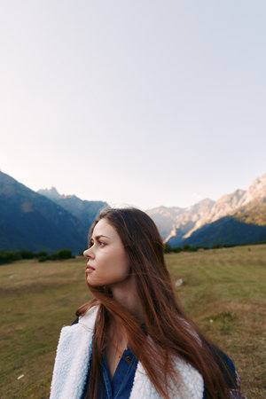 Woman portrait in profile with long hair in mountains meadow outdoors, nature landscape and travel...