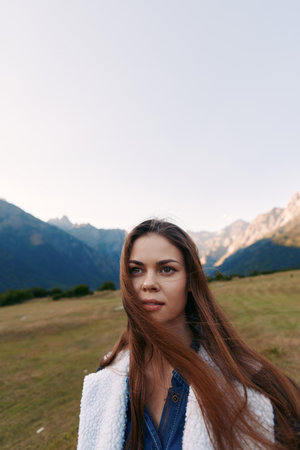 Woman portrait in mountains meadow with longhair blowing in wind, nature outdoor scene, casual young...