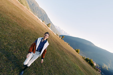 Woman walking in a meadow with mountains in the background, countryside portrait of a young person...