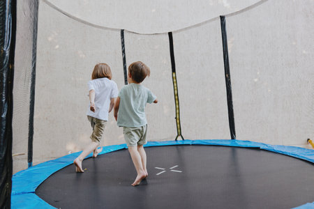 Playful children enjoying time on a trampoline, engaging in fun activities, and sharing laughter under a bright sky.の写真素材