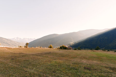 Meadow valley mountains at sunrise over an open field with dry grass and rolling hills, panoramic...