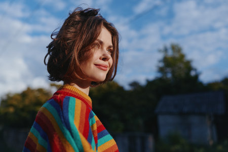Woman, striped sweater, short hair, smiling outdoor portrait of a relaxed young woman in her twenties wearing casual rainbow knit, looking sideways in soft natural light for lifestyle.の写真素材