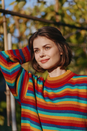 woman portrait smiling in a colorful striped sweater outdoors in autumn sunlight, short hair,...