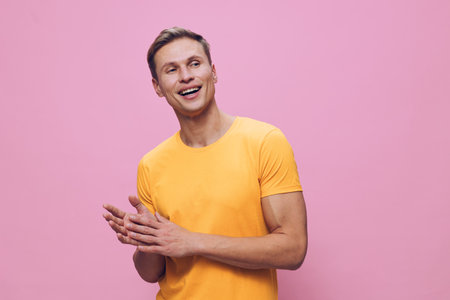 Smiling happy young man wearing yellow t-shirt on pink background studio portrait, cheerful expression, casual style, positive attitude, vibrant colors, lifestyle concept.の写真素材