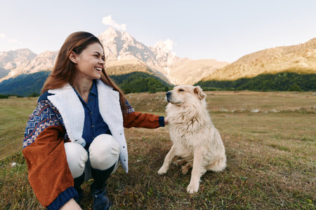 Woman dog mountains meadow smiling pet outdoors nature sitting happy in a mountain meadow, she is petting her dog and smiling during a relaxed outdoor moment with warm sunlight.の写真素材
