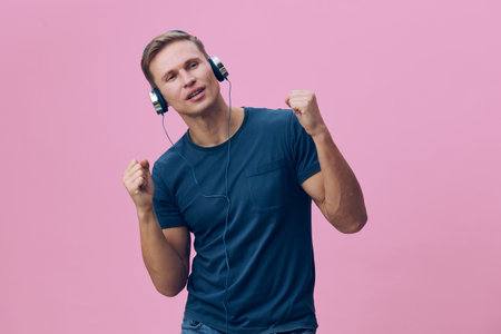 Young man enjoying music, wearing headphones and casual blue t-shirt, expressing happiness and...