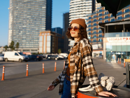 Woman urban candid lifestyle golden sunglasses beanie smile in urban street at golden hour, candid lifestyle portrait with warm smile, authenticity and mindful living for emotional storytelling.の写真素材
