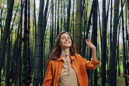 Woman in bamboo forest smiling with eyes closed, portrait of a happy young woman enjoying nature and green surroundings, relaxed outdoor mood and peaceful expression.の写真素材