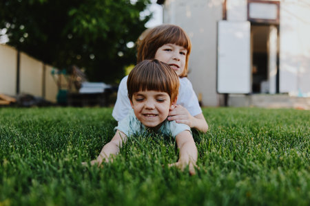Happy children playing together on the grass in a sunny backyard, enjoying a carefree moment of joy and laughter in the fresh air.の写真素材