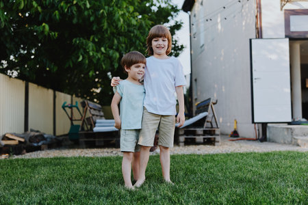 Happy children playing outside in a sunny backyard, enjoying a carefree moment together. Their joyful expressions capture the essence of childhood friendships and laughter.の写真素材