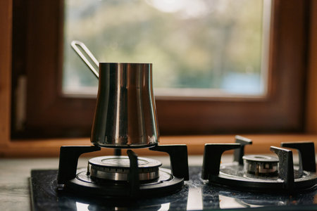Coffee cezve stove kitchen pot gas brewing window authenticity inclusivity metal closeup morning rustic scene of traditional coffee preparation with steam and warm lightの写真素材