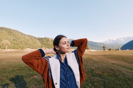 Woman portrait in mountains meadow outdoors, young relaxed in warm jacket looking into distance....