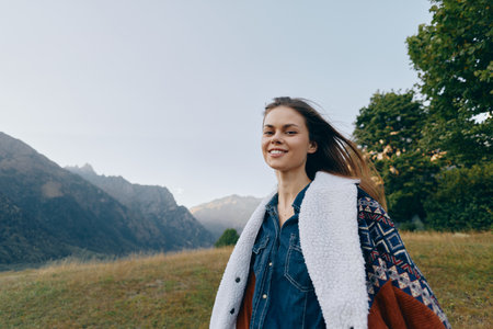 Woman smiling in mountains outdoors nature portrait, young traveler in warm jacket and patterned...