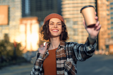 woman coffee smile urban candid beanie sunlight takeaway. Portrait of a young woman holding a takeaway cup at golden hour glow, authenticity and mindful living with emotional storytelling, casualの写真素材
