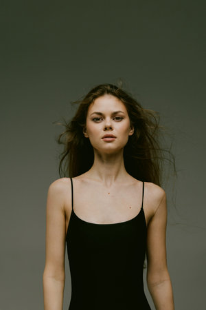 Young woman in black dress looking confidently with neutral background, minimalistic style, natural...