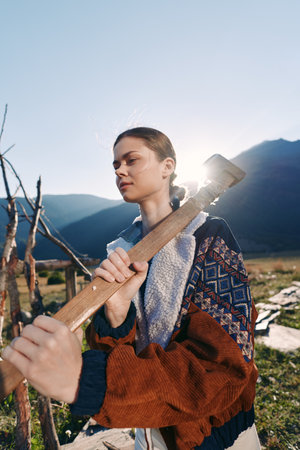Woman with axe and wood in mountains outdoors, rural scene of chopping and nature. Female lumberjack...