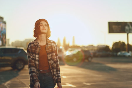 woman walking in urban street at golden hour, sunlight backlight and beanie style, confident candid portrait capturing authenticity, mindful living and emotional storytelling with golden hour glowの写真素材