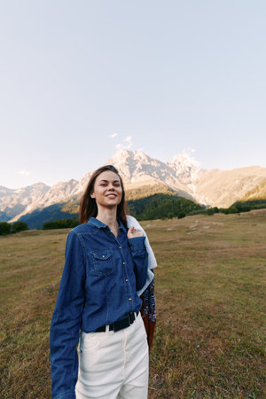 Woman smiling in denim shirt portrait in mountain meadow, casual fashion and travel concept. Outdoor...